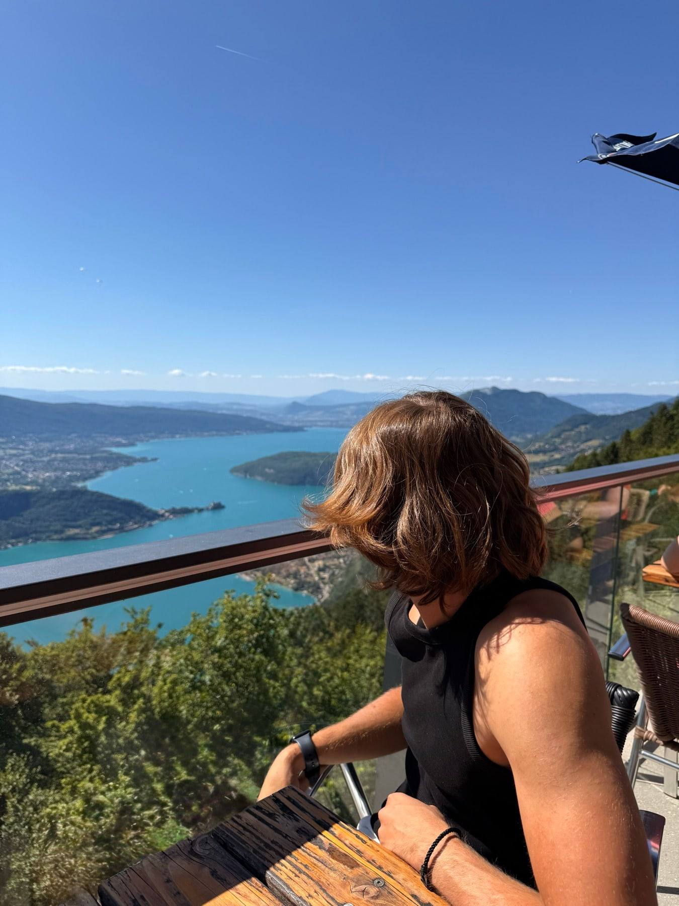 Sinclair looking out over Lake Annecy and the mountains from a balcony.