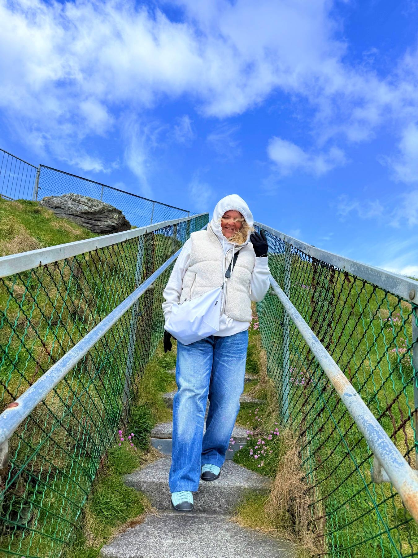 Carine smiling while walking down an outdoor stairway in the mountains.