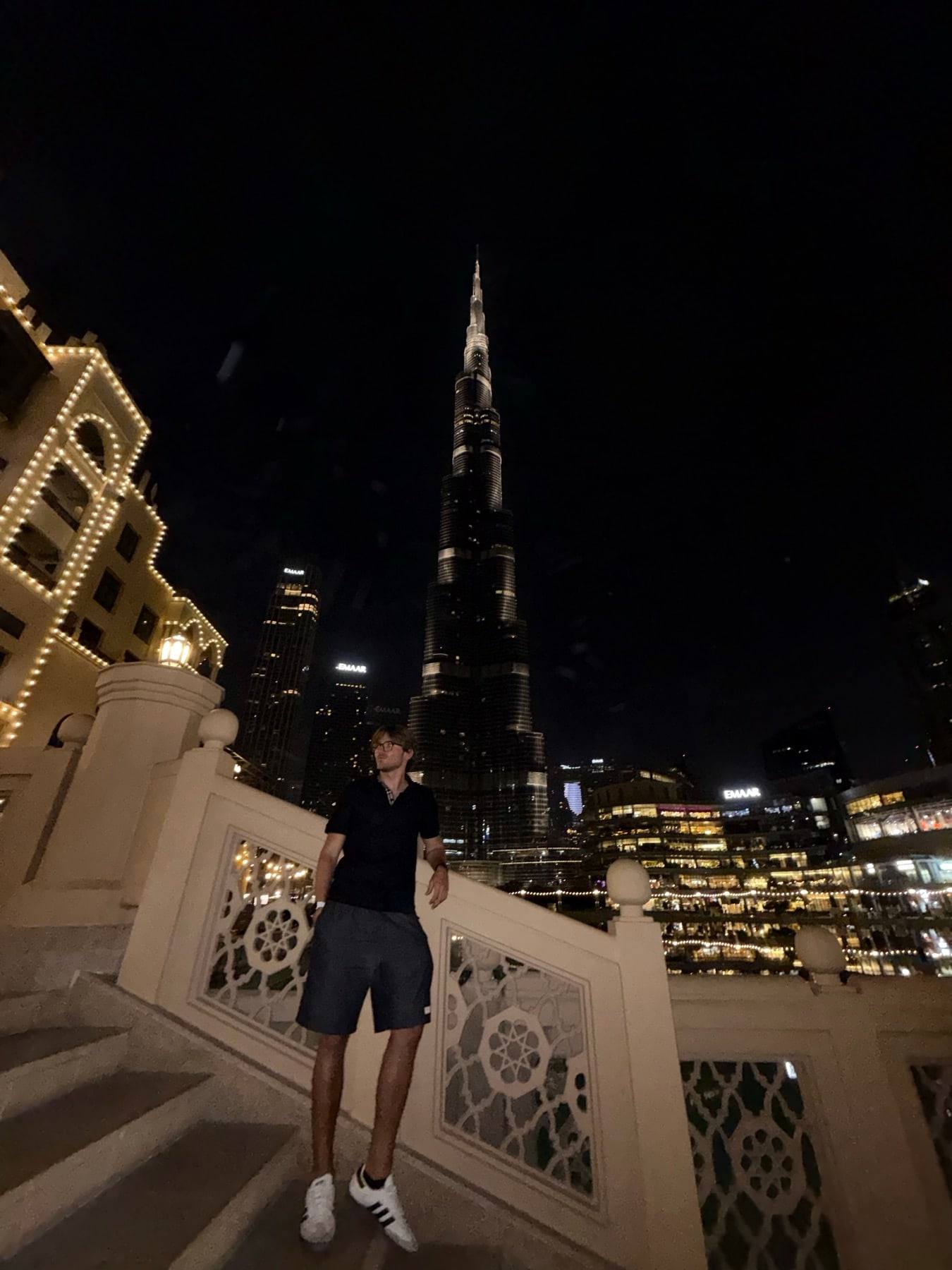 Night view from a terrace towards the Burj Khalifa, with Sinclair on the steps.