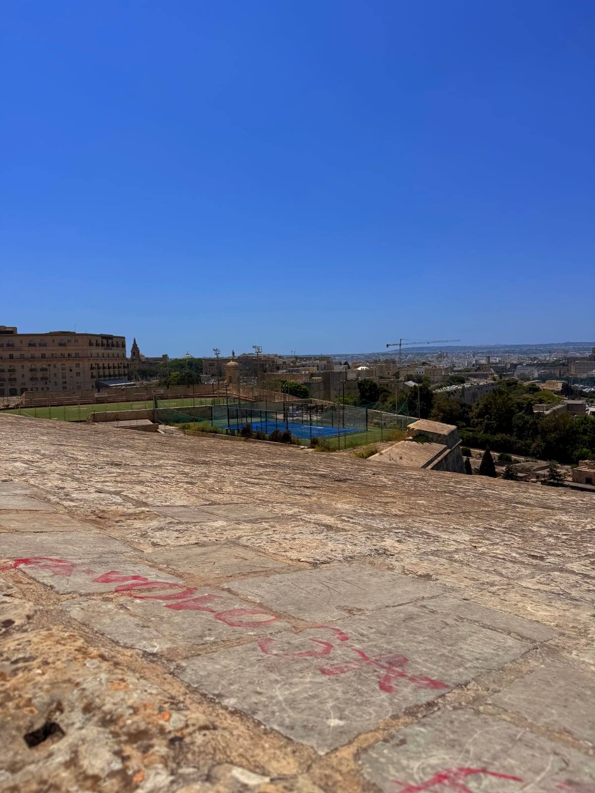 Looking out from old stone ramparts in Valletta, Malta, with paddle tennis courts in the distance.