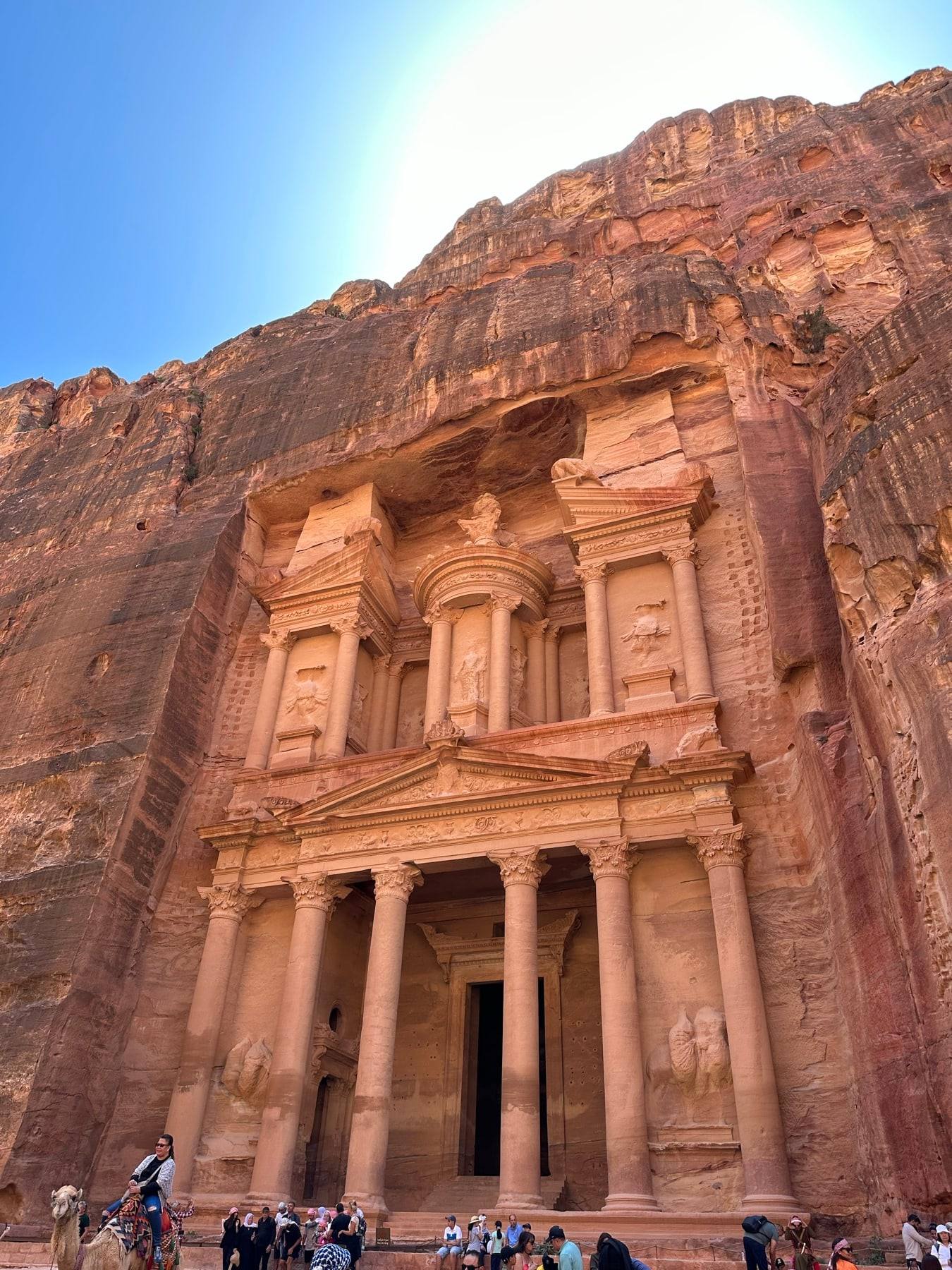 The rose-coloured rock-cut Treasury at Petra against a blue sky.